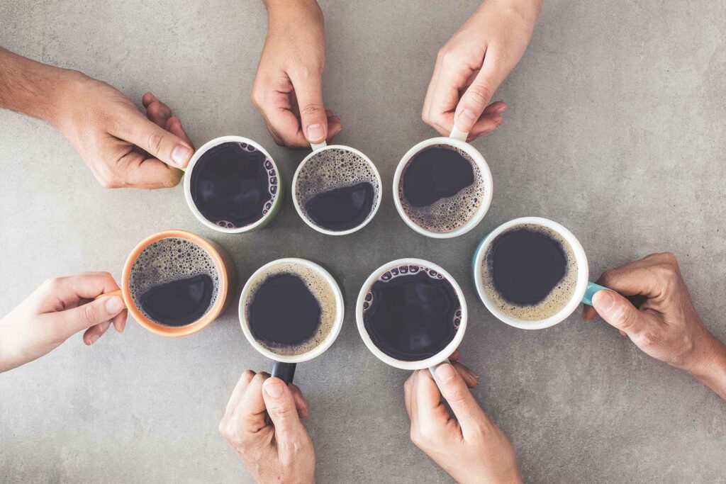7 Hände stoßen zum Morgenkaffee an, Draufsicht