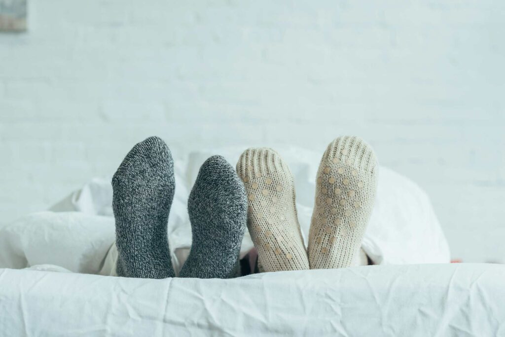 4 Füße in warmen Socken liegen am Bettende